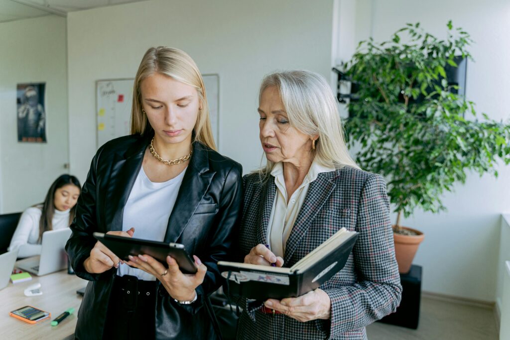 Professional women discussing work in a modern office setting with colleagues.